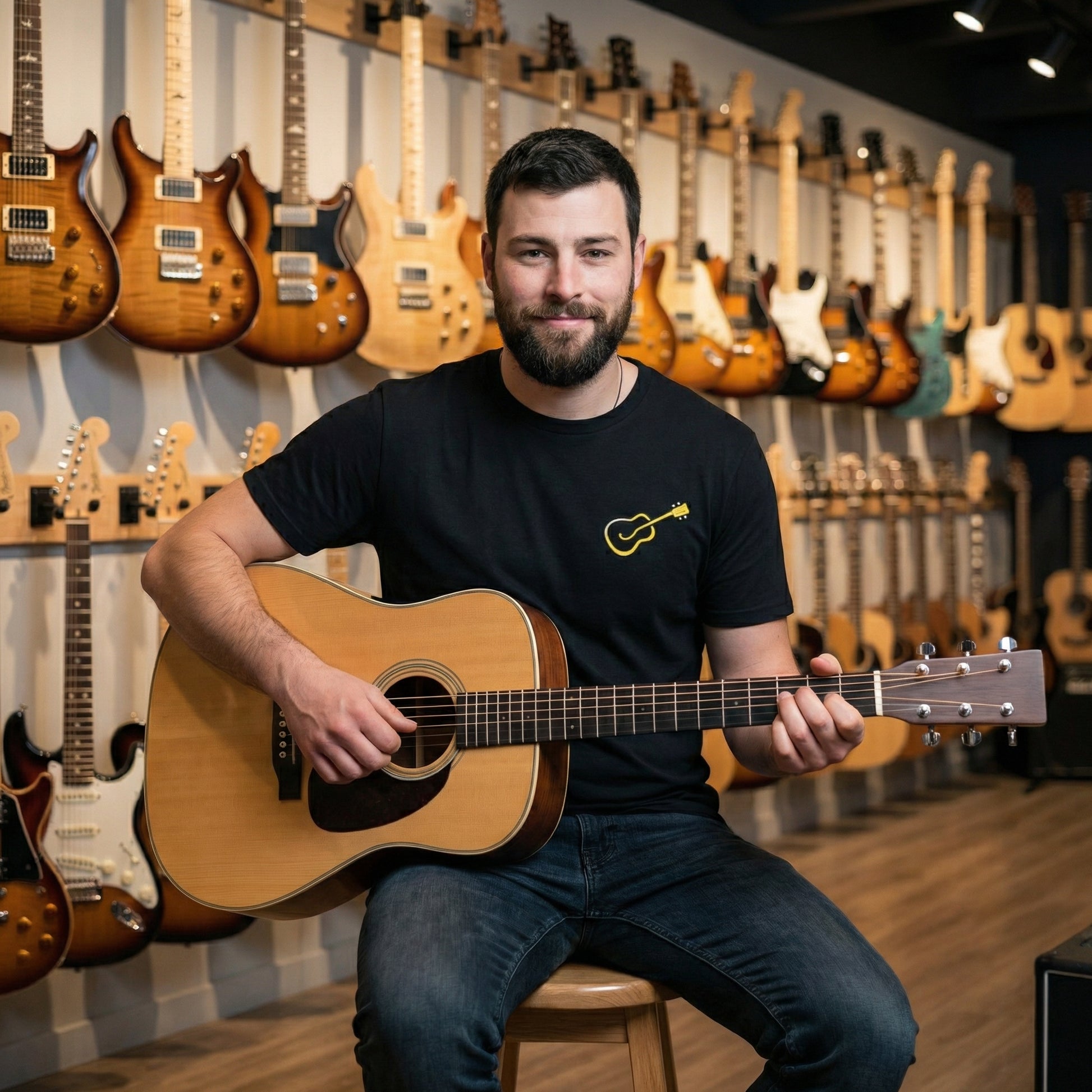 Man holding a guitar in a music store with guitars on the wall behind him