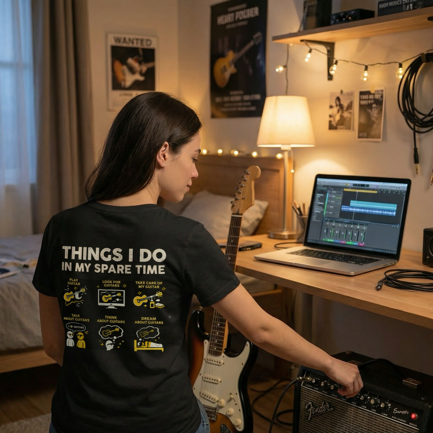 Person in a bedroom setting with a laptop and guitar, wearing a t-shirt with activities listed.